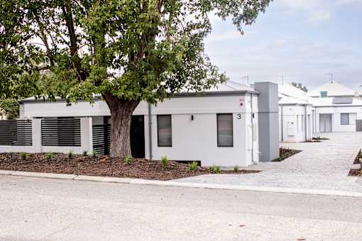 A white building with a tree in front of it.