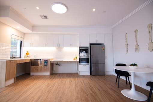 A kitchen with a refrigerator, a table, and a counter.