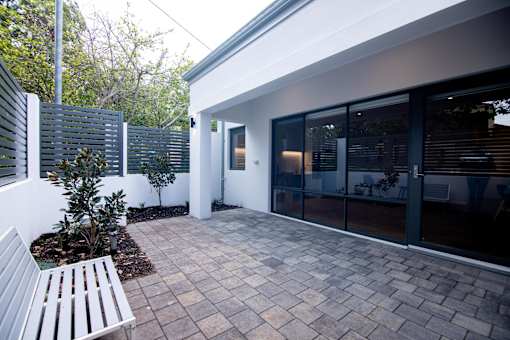 A patio with a bench and a tree.