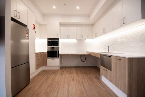 A modern kitchen with wooden floors and stainless steel appliances.