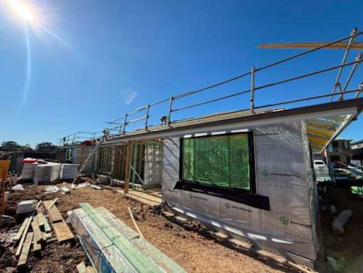 A construction site with a building under construction covered in insulation material.