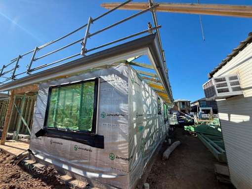 A house under construction with a window covered in plastic.