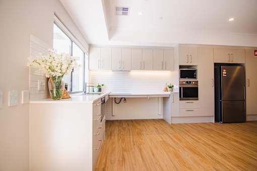 A kitchen with white cabinets and a wooden floor.