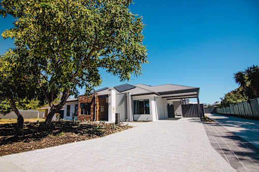 A house with a grey roof and a tree in front of it.