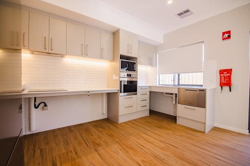 A kitchen with wooden floors and white cabinets.