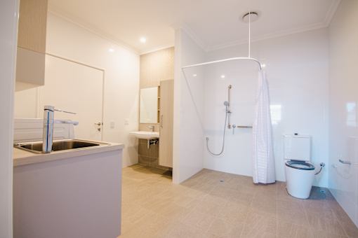 A white bathroom with a sink, toilet, and shower.