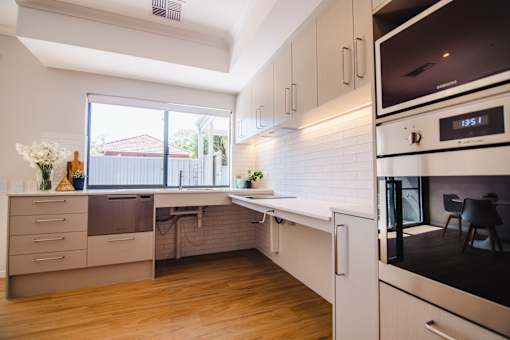 A modern kitchen with white cabinets and a digital clock on the microwave.