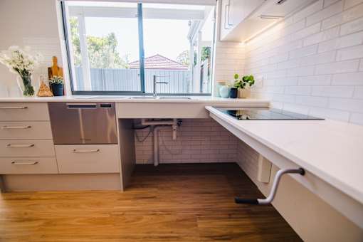 A kitchen with a white counter and wooden floors.