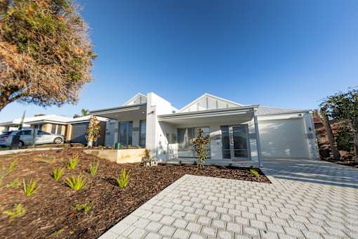 A modern white house with a grey roof and a driveway in front.