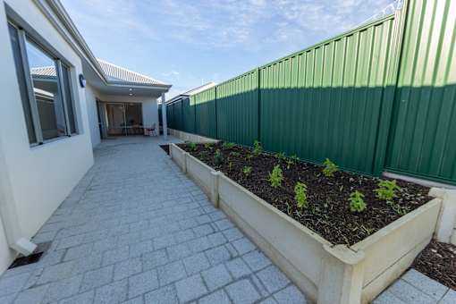 A patio with a planter box and a green fence.