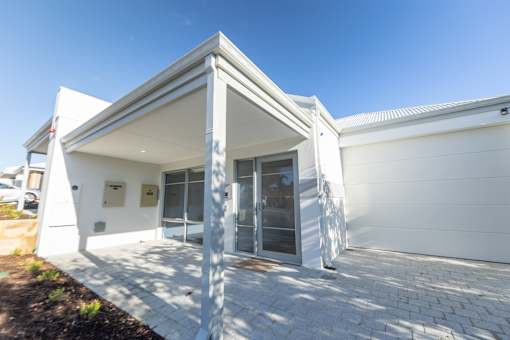 A white building with a triangular roof and a glass door.