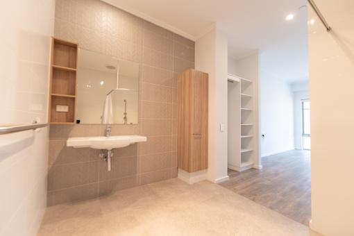 A bathroom with a sink, mirror, and wooden cabinet.