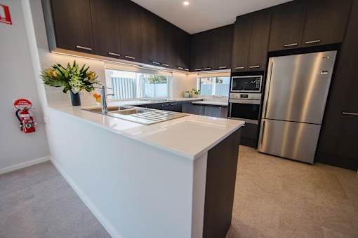 A modern kitchen with dark brown cabinets and a white island.