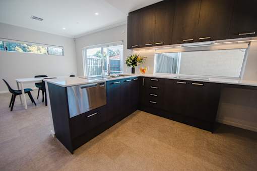 A kitchen with black cabinets and a white counter.