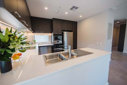 A modern kitchen with a white countertop and stainless steel appliances.
