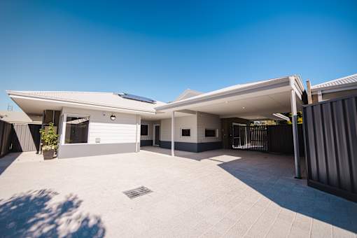 A modern house with a white exterior and a large driveway.