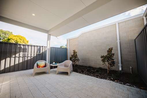 A patio with two chairs and a table with a cushioned chair on it.