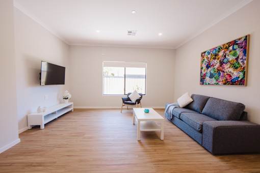 A living room with a grey couch, a television, a chair, and a painting on the wall.