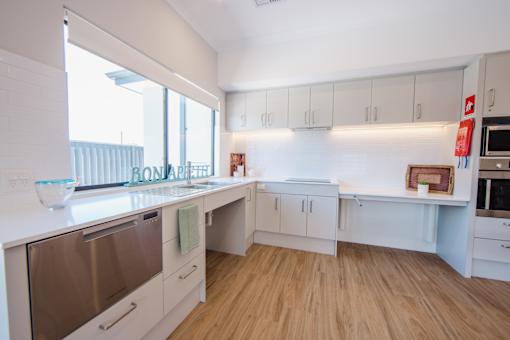 A modern kitchen with white appliances and wooden floors.