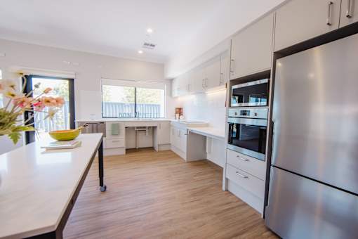 A modern kitchen with a stainless steel refrigerator and wooden flooring.