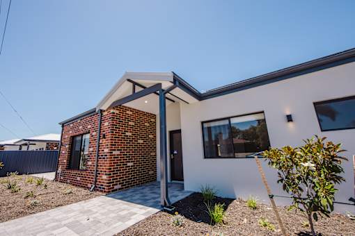 A modern house with a brick chimney and a white exterior.