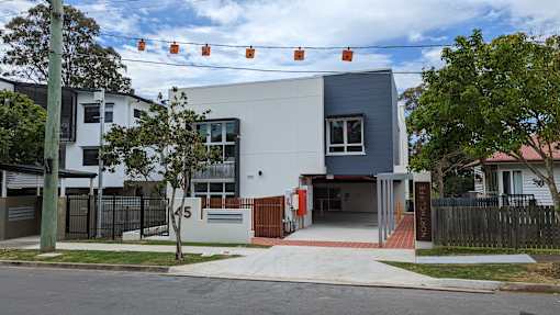 A modern building with a white and grey exterior and a red entrance.