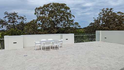 A patio with a table and chairs is surrounded by trees.
