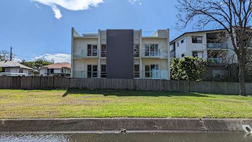 A modern house with a grey facade stands in front of a row of houses.
