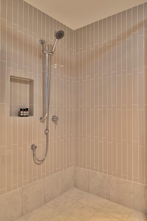 A shower area with a wall of tiles and a shower head.