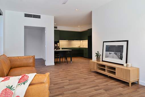 A living room with a brown leather couch and a wooden table.