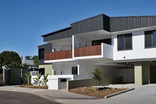 A modern house with a white and black exterior and a balcony on the second floor.
