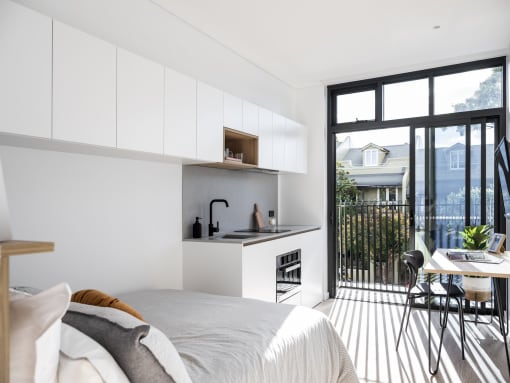 a bedroom with a bed and a kitchen with a balcony