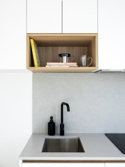 a kitchen sink with a black faucet and a wooden shelf above it