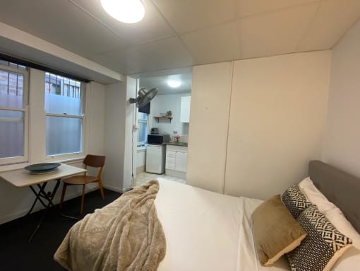 a bedroom with a bed and a desk and a kitchen