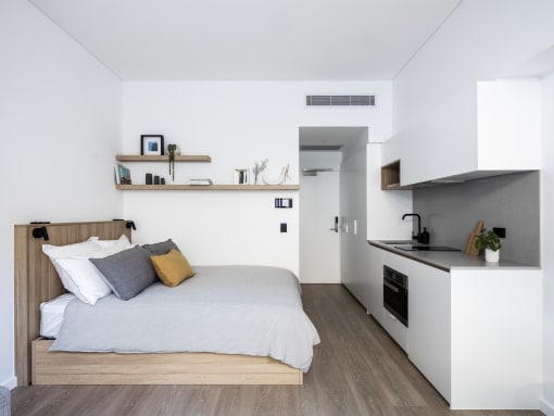a small bedroom with a bed and a kitchen