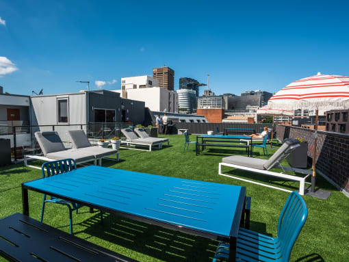 a rooftop patio with tables and chairs and a city in the background