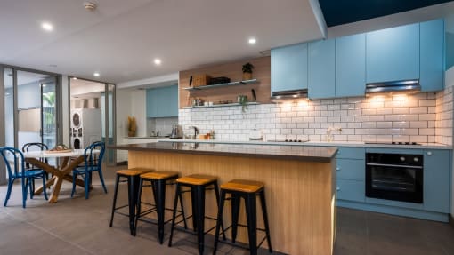 a kitchen with blue cabinets and a bar with four stools