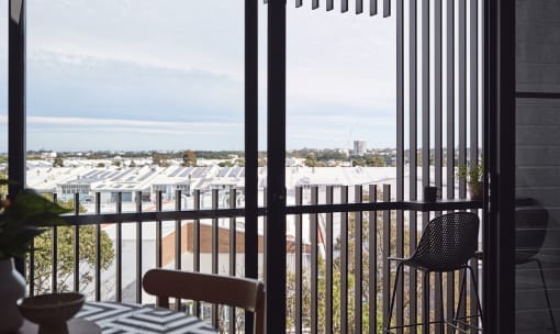 a balcony with a view of a building and a table and chairs