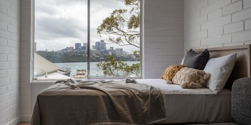 a bedroom with a bed and a window with a view of the city