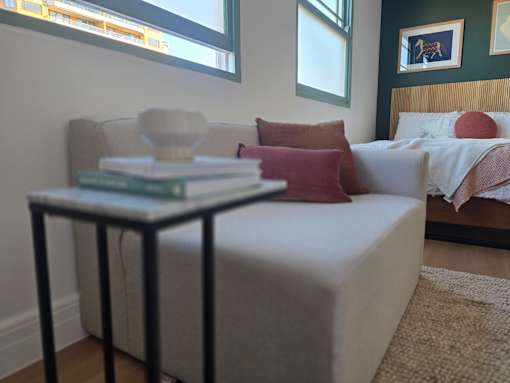 A bedroom with a bed, a couch, and a small table with a book on it.