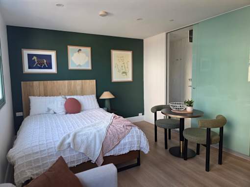 A bedroom with a bed, a table and chairs, and pictures on the wall.