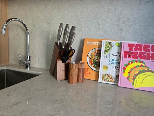 A kitchen counter with a book titled "Mediterranean Cheap Cooking" and a book titled "Taco Fix" on it.