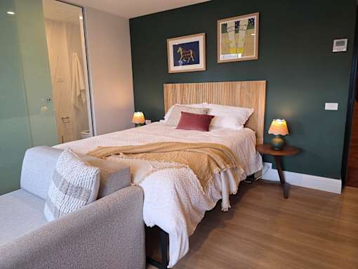 A bedroom with a bed, a chair, and a painting on the wall.
