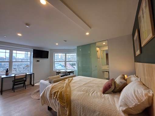 A bedroom with a large bed and a desk with a chair.