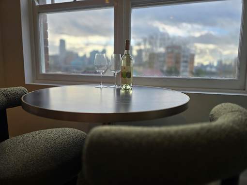 A table with two glasses and a bottle on it in front of a window.