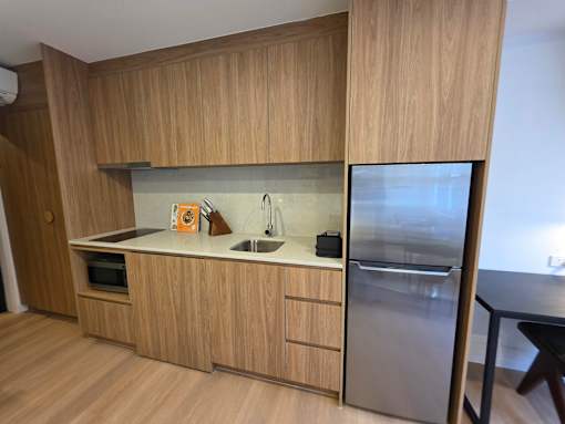 A kitchen with wooden cabinets and a stainless steel refrigerator.