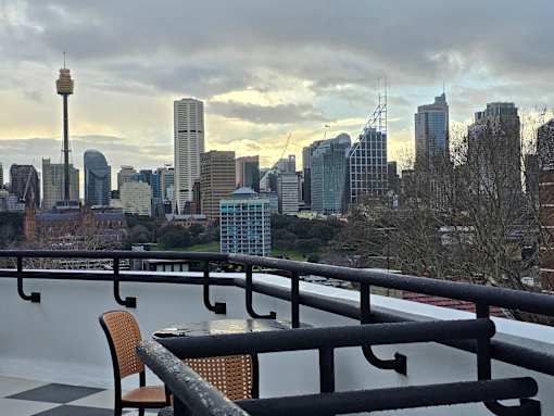 A cityscape with a tall tower and a table with chairs in the foreground.