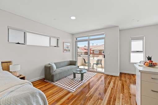 A bedroom with a bed, a couch, a chair, and a table.