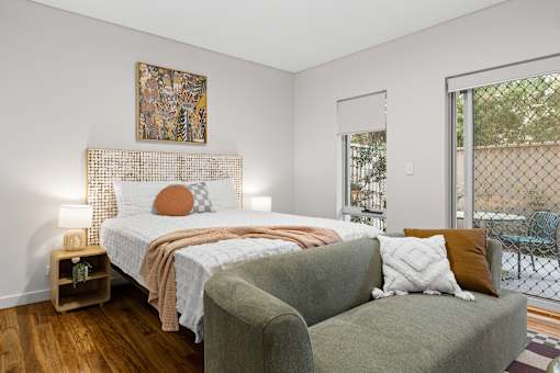 A bedroom with a bed, a couch, and a painting on the wall.