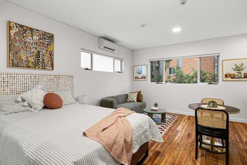 A bedroom with a bed, chair, and pictures on the wall.